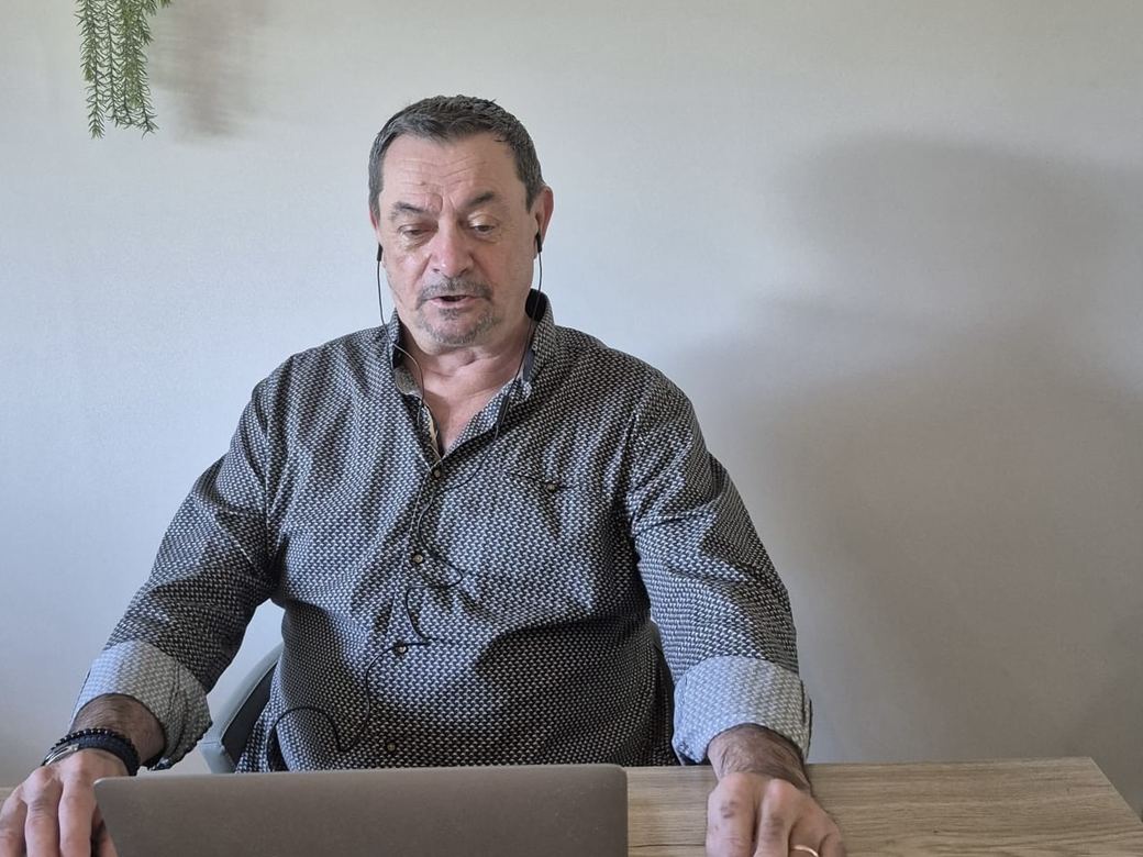 Denis Tallon à son bureau, casque sur les oreilles, pendant une séance en visioconférence
